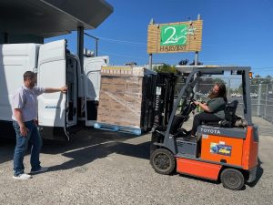 A pallet of food being loaded into an electric vehicle